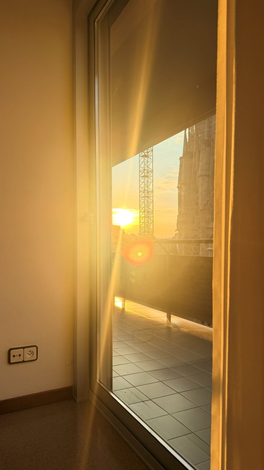 Sunrise cresting over the city through the apartment balcony door